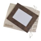 A brown leather photo frame with white stitching placed on a beige drawstring pouch. The words GRADE are partially visible on the pouch.