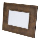 A brown leather photo frame with visible stitching is displayed at an angle. The frame has a rectangular shape and an empty photo slot in the center, backed by a plain white insert.