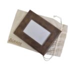 Brown rectangular photo frame with a blank center, resting on a beige drawstring bag. The bag has AGRADE written in brown letters. The frame has a vintage, distressed look.