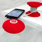 Red retractable cable organizer with UNIQLO logo on a desk, next to a smartphone and a similar organizer with wound cable.