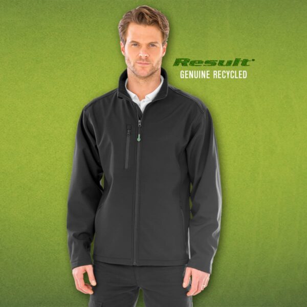 A man wearing a black, full-zip jacket over a white shirt stands against a green background. Text says Result Genuine Recycled.