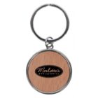 A metal keychain with a round wooden insert. The insert features the logo Merlottes Bar and Grill in black lettering on a wooden background.