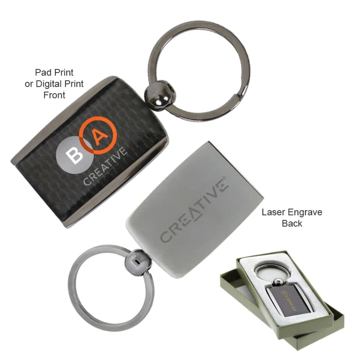 Two metal keychains with a rectangular design. One is black with logo options and labeled Pad Print or Digital Print Front, the other is silver with the text CREATIVE and labeled Laser Engrave Back. Includes gift box packaging.