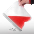 A hand holds a transparent, flexible food storage bag filled with red liquid. The bag is tilted, demonstrating its leak-proof seal. The background is plain white, and the words Leak-Proof Seal are written near the bag.