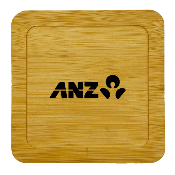 A wooden coaster with a square shape and rounded edges features the ANZ logo in black at the center. The wood grain is visible, giving a natural texture to the surface.