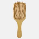 A wooden paddle hairbrush with widely spaced bristles is placed against a plain white background. The handle has a smooth texture, and the brush head is rectangular.