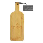 A wooden cutting board with a handle and a black string loop. The board features the word STICKS with a tree-like design above it. Theres a gray rectangle in the top right corner with text saying LOGO AT CUSTOM SIZE.
