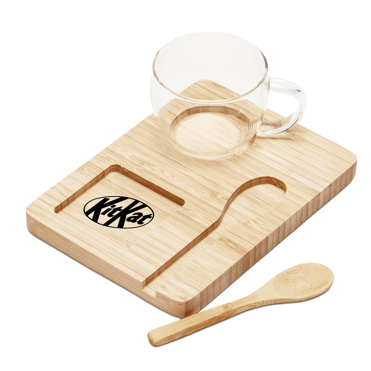 A clear glass cup sits on a wooden tray with a cutout design resembling a KitKat. A small wooden spoon is placed beside the tray.