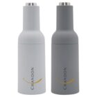 Two sleek bottles with a minimalist design, one light gray and one dark gray. Each bottle features the word Chandon vertically in black and a small curved gold line beneath it. The lids are metallic silver.