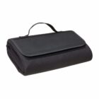 A neatly folded black picnic blanket with a handle on top, featuring a flap cover. The material appears to be soft and compact, suitable for travel or outdoor use.