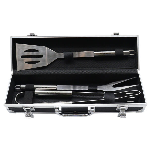 A black case containing three stainless steel barbecue tools: a slotted spatula, a fork, and tongs. The tools are secured with elastic straps. The case has a handle and metal latches for closing.