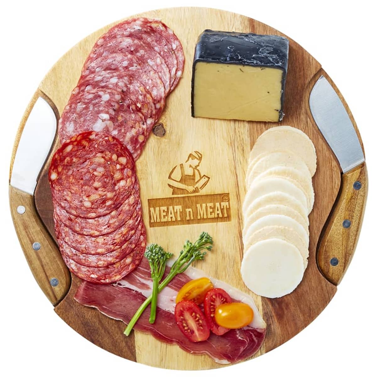 A round wooden board featuring sliced salami, a wedge of dark-rinded cheese, round crackers, and strips of cured meat. Garnished with cherry tomatoes and broccoli. Two decorative knives rest on the sides of the board.