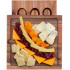 A wooden serving board with a clear tray displays a selection of cheeses, dried apricots, and cranberries. Cheeses include white cubes, triangular slices of cheddar, and creamy wedges, arranged attractively.