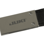 Close-up of a metallic USB flash drive with JUKI printed on it in black letters. The drive has a rectangular shape and is attached to a black strap. Two small screws are visible on the metal surface.