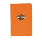 Orange notebook with the Harley-Davidson logo centered on the front cover. The logo features a shield shape with Harley-Davidson Motor Company text. A yellow ribbon bookmark is slightly visible.
