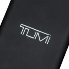 A close-up image of a black surface displaying the white TUMI logo in the center.