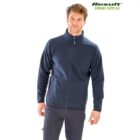 A man is wearing a navy blue zip-up fleece jacket and dark pants, standing against a white background. The jacket has pockets and a high collar. Result Genuine Recycled is printed in green text at the top-right corner.
