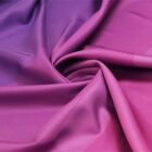Close-up of a fabric with a gradient transitioning from deep purple to pink. The fabric is smoothly arranged and slightly gathered in soft folds, creating a swirling texture and a rich, vibrant color effect.