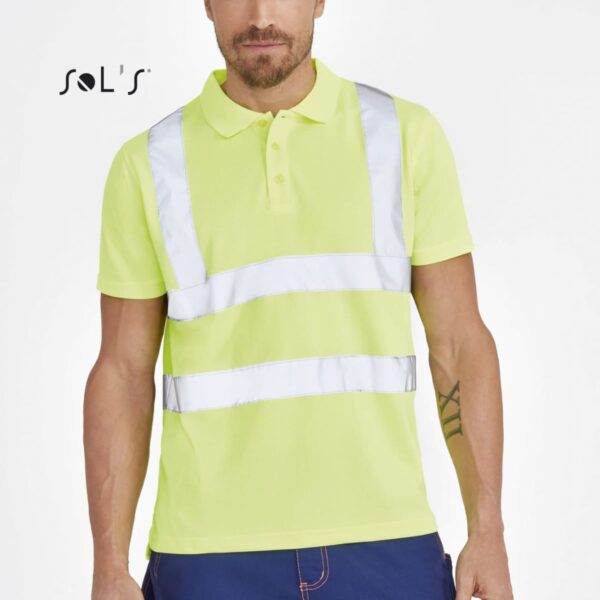 A man wearing a neon yellow polo shirt with reflective strips stands against a plain background. He is also wearing blue pants with red stitching. The text SOLS appears on the left side of the image.