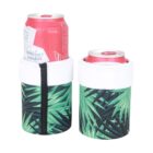 Two red cans in tropical-themed, green and black drink coolers with palm leaf patterns. One cooler is zippered with a black seam, and both have a white top border.