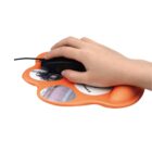 A hand is using a black wired mouse on an orange, paw-shaped mouse pad featuring three circular images, including a motorcycle and a coastal scene. The mouse pad has a wrist support cushion.