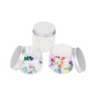 Three clear jars with silver lids are on display; two contain colorful push pins, while the third jar is empty.