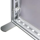 Close-up of a gray floor-standing banner display with a lightweight aluminum frame. The image shows a corner of the stand, revealing cables and a row of small circular LED lights along the bottom edge.