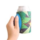 Hand holding a white can wrapped in a colorful, abstract-patterned beverage cooler with a blue grip.