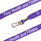 Close-up of a purple lanyard with white text reading Your Health and Fitness. It features a silver metal clip for attachment.