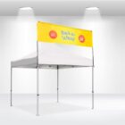 White canopy tent with a promotional banner on top that reads Back to School in yellow letters. The banner also displays Special Offering and 50 in red circles. The tent is set in a bright, spotlighted area.