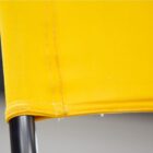 Close-up view of a yellow fabric seat with visible stitching on black metal legs. The fabric appears tightly stretched and well-fitted, showcasing a modern and minimalist design.