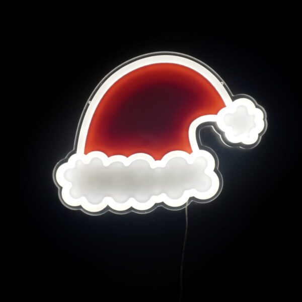 Neon sign of a red Santa hat with a white trim and pom-pom glowing against a black background.