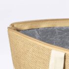 Close-up of a beige woven bag with a zipper partially open. The interior is lined with a silver, metallic-looking material. A white strap is visible on the side, suggesting a handle. The background is plain white.