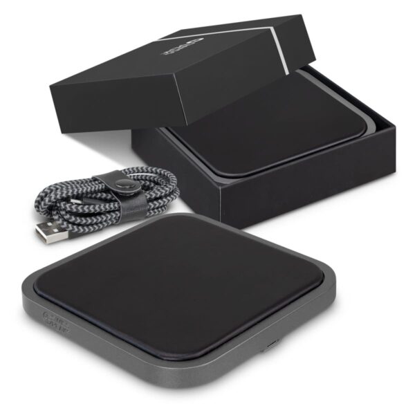 A sleek, black wireless charging pad is displayed with its open box and a braided USB cable. The charging pad has a rectangular shape with rounded edges and a simple design.