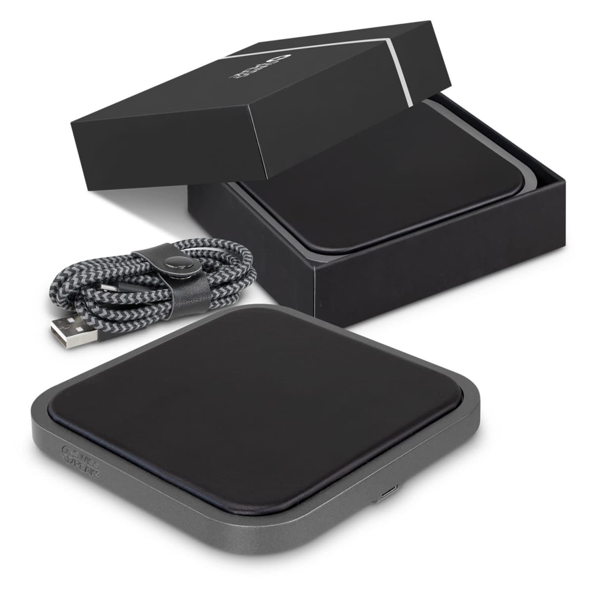 A sleek black wireless charger rests on a white surface, partially slid out from its matching box. Beside it, a braided USB cable is neatly coiled and secured with a leather strap.