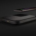 A smartphone is hovering above a wireless charging pad labeled Swiss Peak against a dark background. The phone screen shows a battery charging icon. The charging pad has a sleek, black design with visible USB ports on the side.
