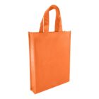 An orange reusable tote bag with sturdy handles is standing upright. The bag has a rectangular shape and appears made of non-woven fabric, suitable for carrying groceries or daily essentials.