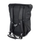 A black backpack with padded shoulder straps and a front chest buckle. The main compartment has a roll-top closure. The fabric has a textured appearance, and there are side pockets on both sides. The backpack appears sturdy and spacious.