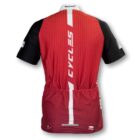 Red and black cycling jersey displayed from the back, featuring vertical stripe design, CYCLES text in the center, and brand logos on the upper and lower sections. The sleeves are black with white logo details on the left sleeve.