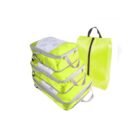 A set of four lime green travel packing cubes and one lime green packing bag with a black zipper. Each packing cube features a mesh top and handles.