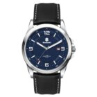 A wristwatch with a blue dial featuring the Suzuki logo. The watch has silver hour markers and a date display at 3 oclock. It includes a black leather strap with white stitching.