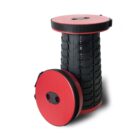 Collapsible stools with black accordion-style bodies and red seats and bases. The upright stool is fully extended, while the other is compact and lies flat.