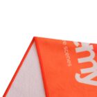 Close-up of an orange and white cloth, focusing on the corner. The orange side features partial white lettering, and the visible stitching along the edges is in orange.