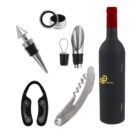 Wine accessory set with a bottle, corkscrew, foil cutter, stopper, pourer, and ring. The bottle is black with a red cap and Brand logo. Accessories are silver and black, arranged neatly around the bottle.