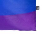 Close-up of a fabric bag corner showing a color transition from blue to purple. A small tag with black and white design is attached to the edge. The texture appears slightly textured, indicating it might be made of a durable material.