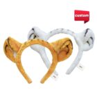 Two plush headbands with animal ears: one in orange-brown with black stripes resembling a tiger, the other in white with black stripes resembling a zebra. A custom label is in the top right corner. Tags attached to each headband.
