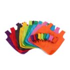 A collection of reusable shopping bags in various vibrant colors, including red, purple, black, green, yellow, and blue, spread out in a fan shape. Smaller, folded versions of these bags are stacked on the rightmost orange bag.