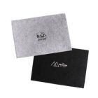 Two gray and black felt folders are shown. The gray folder has a panda logo and text, while the black folder shows a mountain logo with the text THE PAVILION and Est. 1976.