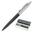 A sleek black and silver ballpoint pen with American Express engraved on the metal clip, displayed next to its open box labeled Parker. The box shows the pen nestled inside on a white lining.