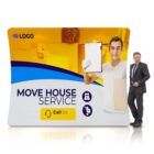 A man in a suit stands next to a large billboard for a moving service. The billboard features a person holding a clipboard and a box, with contact icons and text that reads Move House Service and Call Us. The background is yellow and blue.
